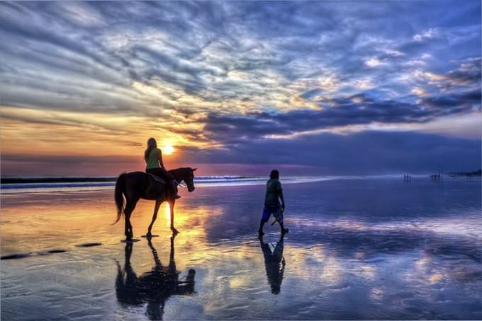 Girl riding a horse at sunset on Bali